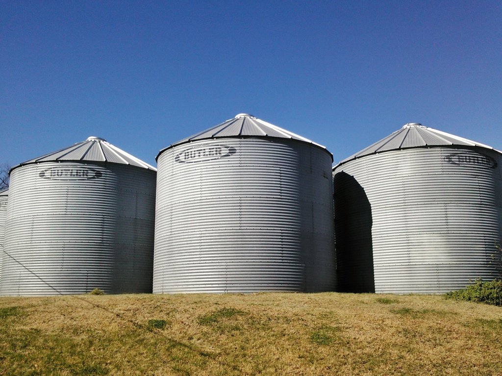 These are grain bins. Unlike a silo, bins are used to store dry feeds like corn or soybeans.  Silos on the other hand hold things that are wetter and that you want to ferment.  Thanks to my friend Nicole for sending me a photo of their grain bins. Click on this photo to visit her blog! 