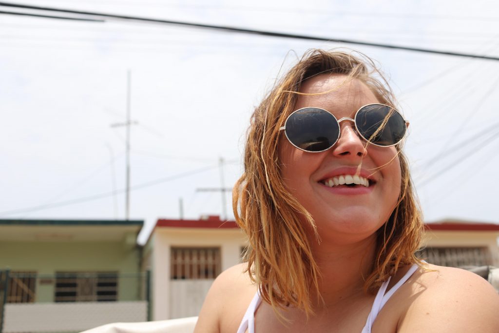 Young woman with brown hair wearing sunglasses and smiling